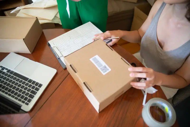 Online retailer packing an order next to a laptop